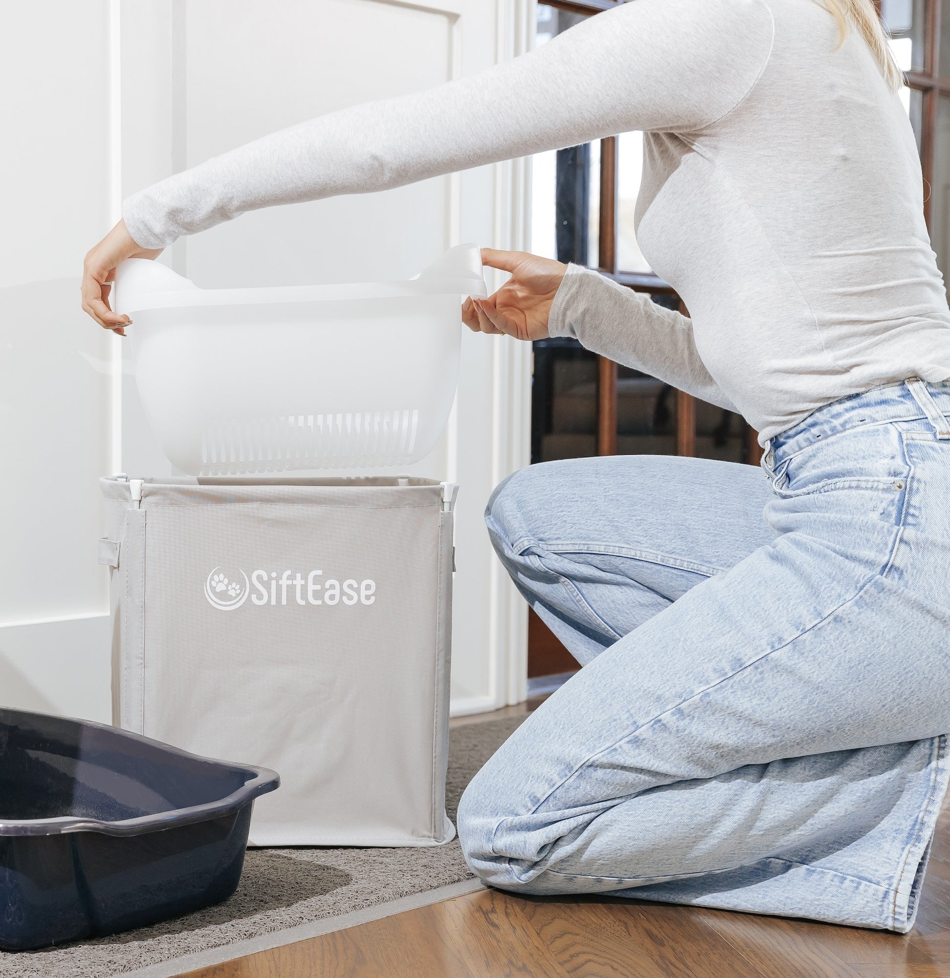 Cat owner lifts the durable sifting tray basket from the SiftEase litter catching bin